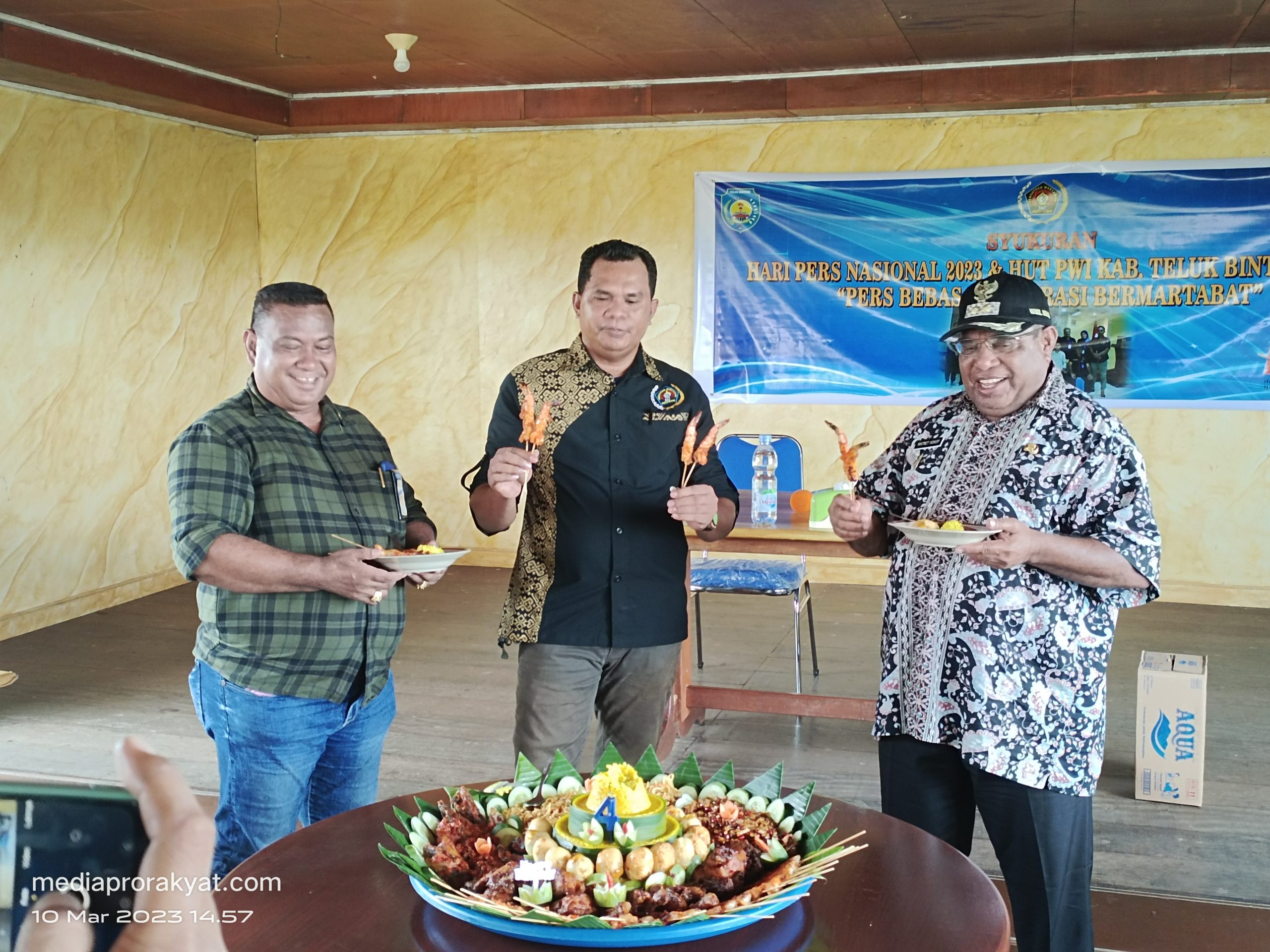 Wakil Bupati Teluk Bintuni dan Kabag Humas memegang potongan tumpeng yang diberikan oleh Ketua PWI Teluk Bintuni saat kegiatan syukuran ,Jumat (9/3/2023)