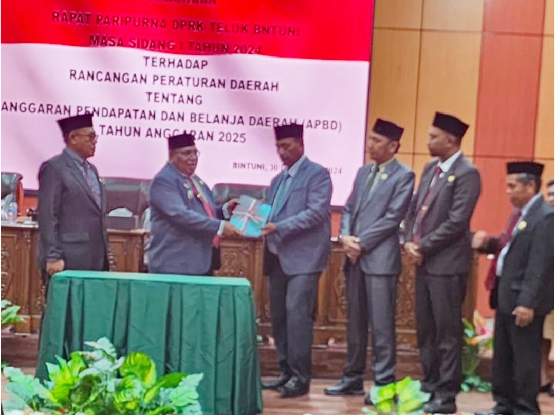 Bupati Teluk Bintuni, Matret Kokop, S.H., didampingi Asisten II, Ida Bagus Putu Suratna, menyerahkan dokumen Raperda APBD 2025 kepada Ketua I DPRK Teluk Bintuni, Romilus Tatuta. Penyerahan tersebut turut didampingi oleh Wakil Ketua II DPRK Teluk Bintuni, Yasman Yasir, dan Wakil Ketua III DPRK Teluk Bintuni, Budi Irianto Nawarisa, pada Selasa (31/12/2024).