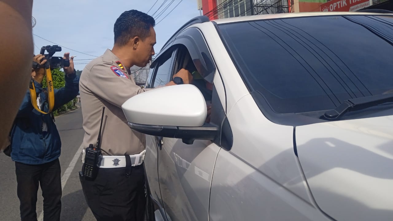 Kasatlantas Polresta Manokwari,Iptu Nurfah saat membagikan coklat dan bunga kepada pengendara mobil