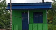 Keterangan gambar: Tampak sebuah bangunan dari konstruksi kayu yang dicat hijau, dengan pintu, jendela, dan atap berwarna biru. Bangunan ini diduga merupakan hasil proyek BUMDes di Kampung Kalitami II , Distrik Kamundan, Kabupaten Teluk Bintuni. Foto diambil dari sisi depan dan diunggah oleh pemilik akun Facebook Iribaram OM Dorang. (Foto: Istimewa)