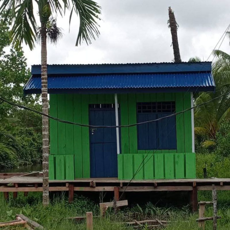 Keterangan gambar:
Tampak sebuah bangunan dari konstruksi kayu yang dicat hijau, dengan pintu, jendela, dan atap berwarna biru. Bangunan ini diduga merupakan hasil proyek BUMDes di Kampung Kalitami II , Distrik Kamundan, Kabupaten Teluk Bintuni. Foto diambil dari sisi depan dan diunggah oleh pemilik akun Facebook Iribaram OM Dorang. (Foto: Istimewa)