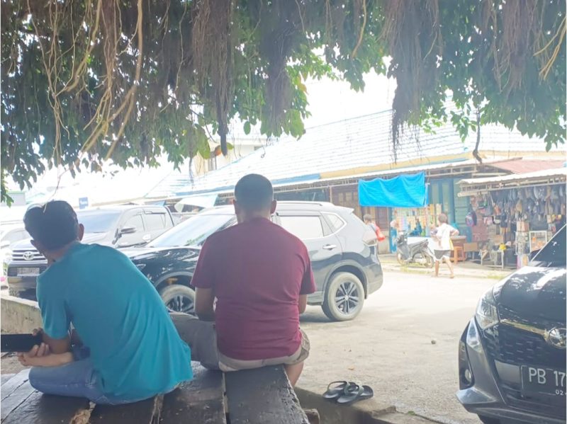 Tampak Dua  sopir tengah menanti rejeki di bawah rindangnya pohon beringin di Pasar Sentral Bintuni. Tak jauh dari sana, seorang warga menjajakan berbagai jenis minuman. Sebuah potret keseharian para pengais rejeki. Rabu (6/8).
